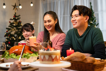 Happy Asian family mother, father and daughter having dinner celebrating Christmas at home	