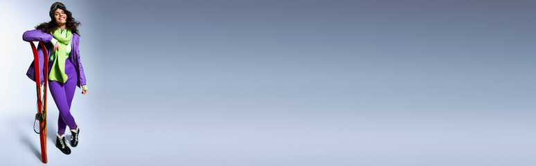 winter banner, happy woman with brunette hair posing in active wear with puffer jacket and skis