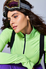 portrait of charming sporty woman with curly hair posing in trendy active wear on grey backdrop