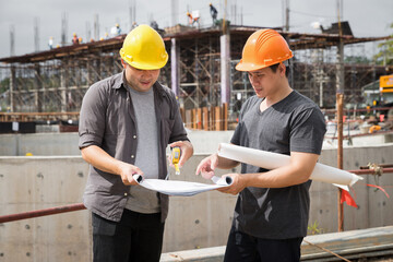Team of construction workers discussing project details with blueprint in construction site. - obrazy, fototapety, plakaty