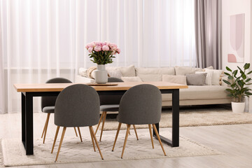 Table, chairs, sofa and vase with peonies in stylish dining room