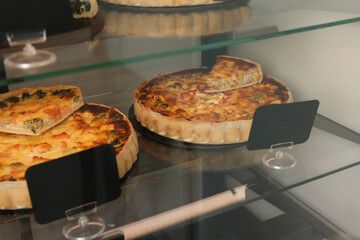 Different delicious quiches on counter in store