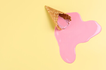 Melted ice cream and wafer cone on pale yellow background, top view. Space for text