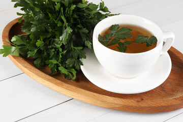Aromatic herbal tea and fresh parsley on white wooden table