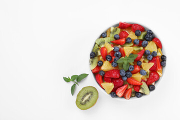 Yummy fruit salad in bowl on white background, top view. Space for text