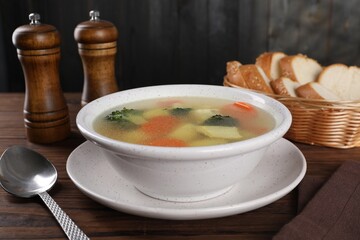 Tasty chicken soup with vegetables in bowl served on wooden table, closeup
