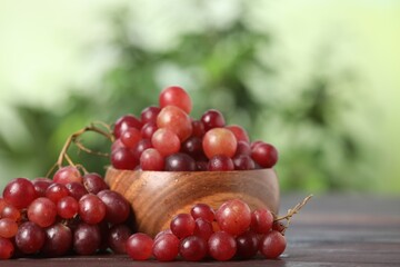 Delicious fresh red grapes on dark wooden table. Space for text