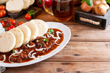 Traditional czech goulash with dumplings (knedliky) and beer on table. Place for text. Copy space