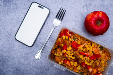Mockup of a phone next to healthy food in a lunchbox. Taking takeaway food to work or school