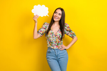 Photo of cheerful girl with long hairdo dressed flower print blouse look at dialog cloud in hand isolated on yellow color background