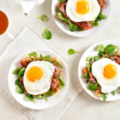 Fried eggs, bacon and vegetable leaves on toasted bread o