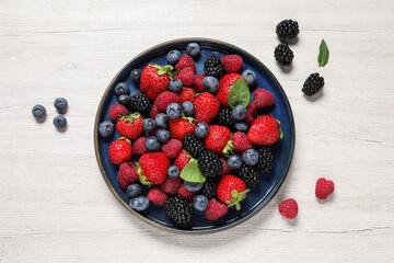 Different fresh ripe berries on light wooden table, flat lay