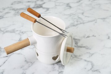 Fondue set on white marble table. Kitchen equipment