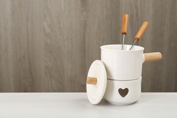 Fondue set on white wooden table, space for text