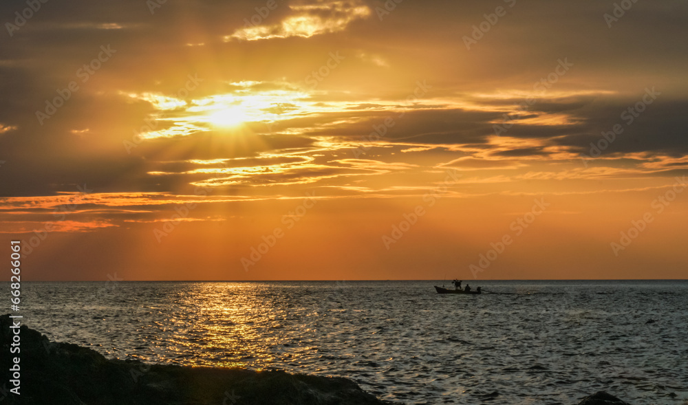 Sticker A small fishing boat moored in the middle of the sea during sunset in Thailand.