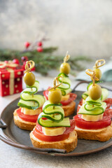 Creative appetizers christmas. Christmas tree canapes of salami, cheese, olives, tomatoes and cucumbers on a baguette. Copy space.
