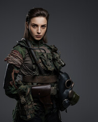 Confident female soldier in military attire posing against a gray backdrop, representing the Middle East conflict