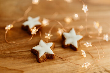 Gingerbread cookies in the shape of stars on a wooden brown natural table against a background of bokeh of New Year's golden lights. Christmas background. Winter card. Delicious pastries close-up