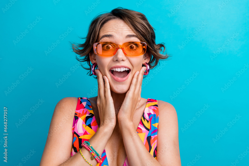 Poster Portrait of ecstatic overjoyed person with bob hairdo wear colorful dress in sunglass astonihsed staring isolated on blue color background