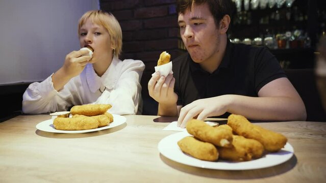 A girl and a boy - teenagers eat hot cheese sticks with sauce in a cafe. Close-up.
