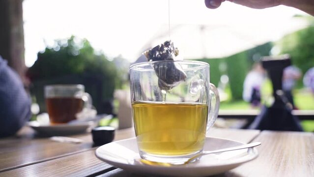 A man brews green tea in a triangular bag in a cup. Close-up.