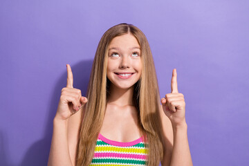 Photo of cute schoolgirl with straight hairdo dressed striped top look directing at sale empty space isolated on violet background