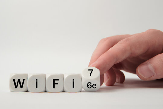 Hand turns dice and changes the expression "WiFi 6e" to "WiFi 7" on white background