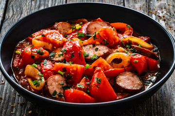 Delicious letcho - vegetables with sausages on wooden table
