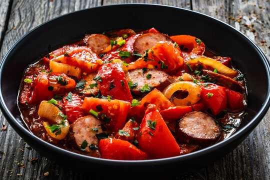 Delicious letcho - vegetables with sausages on wooden table
