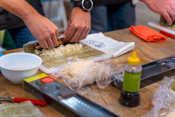 Sushi cooking workshop. Sushi chef rolls the rice with the mat.