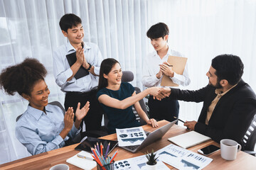 Diverse coworkers celebrate success with handshake and teamwork in corporate workplace. Multicultural team of happy professionals united in solidarity by handshaking in office. Concord