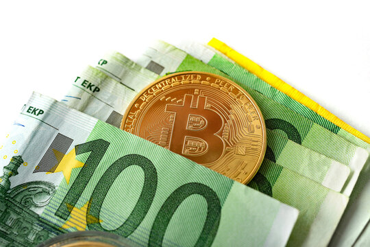 Criptomonedas y tecnolog&iacute;a.
Monedas de oro Bitcoin con billetes de euro sobre fondo blanco, imagen de primer plano.