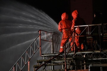Fireman with red safety uniform fire fighter by high pressure water jet