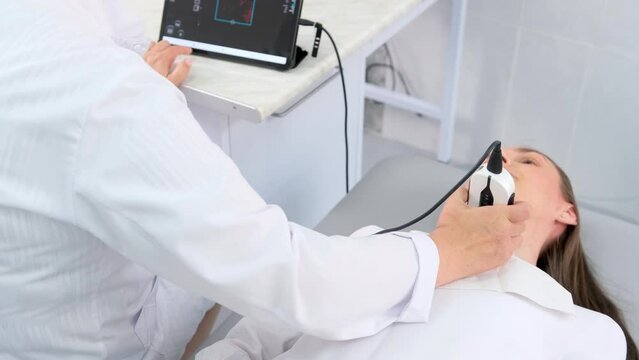 a doctor in a modern diagnostic clinic examines the thyroid gland of a patient of a young attractive woman on an ultrasound machine. Prevention of thyroid cancer