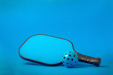 Blue Pickleball paddle with Blue Pickleball on a Blue background...room for text.