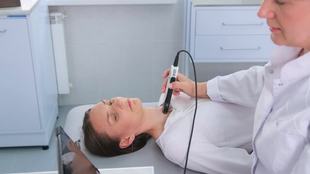 a doctor in a modern diagnostic clinic examines the thyroid gland of a patient of a young attractive woman on an ultrasound machine. Prevention of thyroid cancer