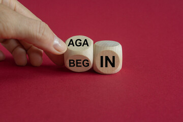 Businessman turns wooden cube and changes the words begin to again. Beautiful red background. Business and begin again concept. Copy space.