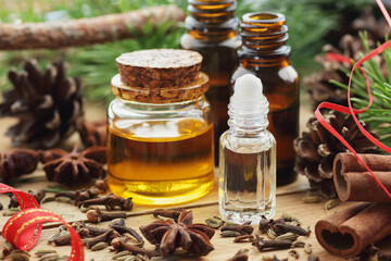 Essential oil bottles with cinnamon, star anise, clove, pine oils on wooden rustic background, closeup, aromatherapy, natural medicine, winter christmas holiday care concept