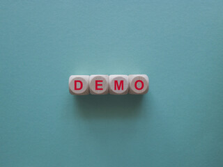 The red word Demo on wooden cubes. Blue background. An extensive concept of the word demo applied...