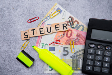 the inscription steuer, i.e. tax, next to banknotes and a calculator. Concept showing taxes in...