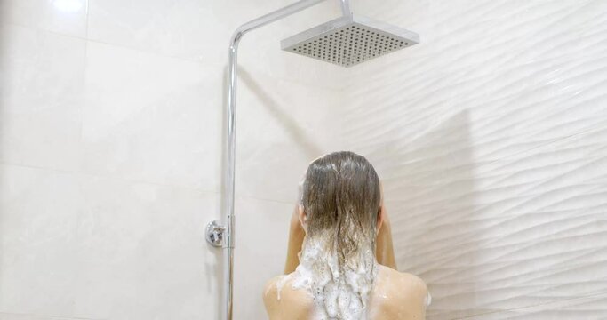 Pretty young woman taking a shower and shampooing her hair, health care concept.