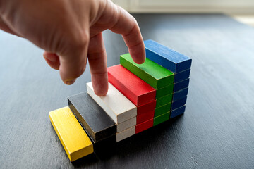 close up of businessman hand climbing upstairs on color wooden block,