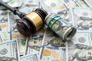 Gavel above piles of new 100 dollars bills as finance background.  Justice concept