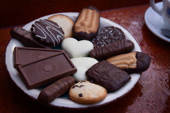 Image of a plate of assorted chocolate cookies on a tray with cups of coffee
