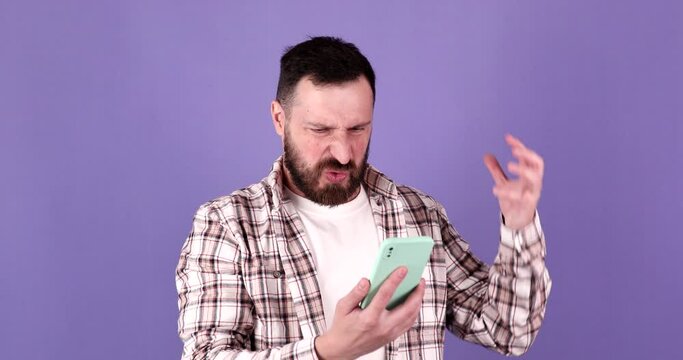 Annoyed young bearded man quarreling while talking on mobile phone. Angry man, stress.