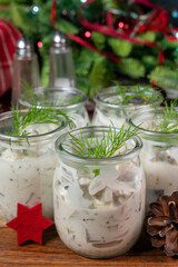 Pieces of herring in yoghurt with dill served in small jars.