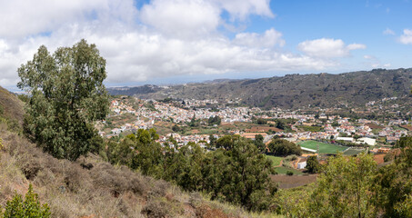 Fototapeta na wymiar Beautiful panoramic view of Teror between hills covered by green vegetation on sunny day in Gran Canaria island, Spain