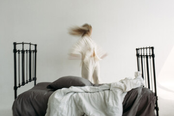 There is a bed in the middle of the room, and a woman is running in the background. The image is...