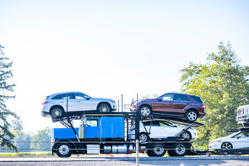 Profile of the running blue big rig classic car hauler semi truck transporting cars on the modular...