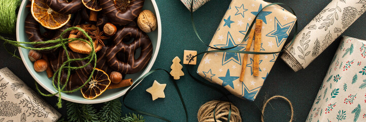 Preparing for the holiday, wrapping gifts under the Christmas tree in craft paper, Merry Christmas and New Year banner, plate with cookies and dry tangerine slices